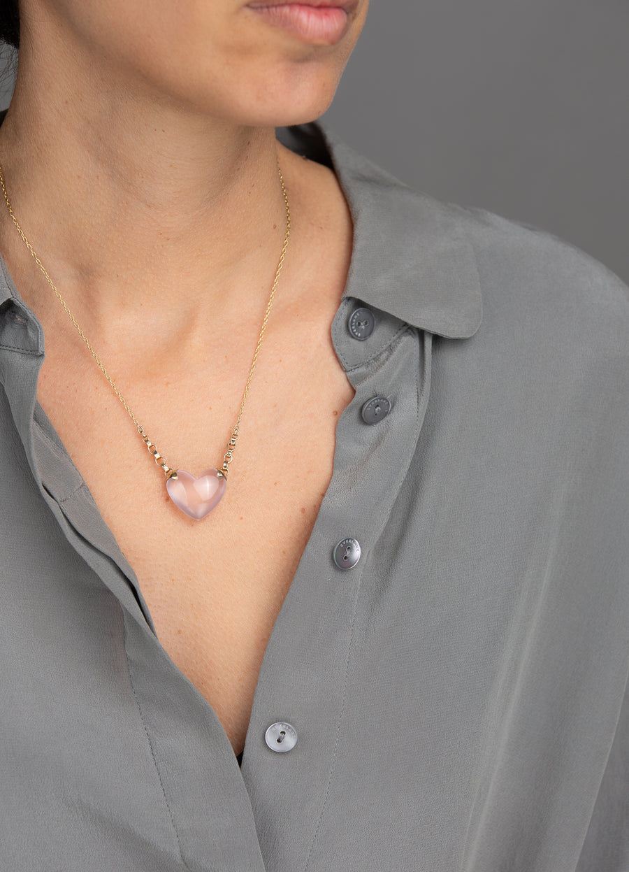 woman in grey modeling rose shiny puffy quartz heart necklace with side gold shackles leading up to gold chain