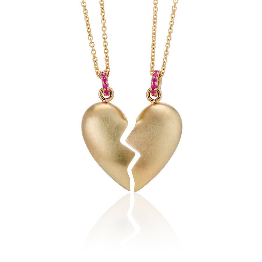front view of pair of shared heart puffy necklaces made in 14k yellow gold with a brushed finish but shiny interior finish where heart is cut in half jagged. Rubies on bail in gold necklace chain