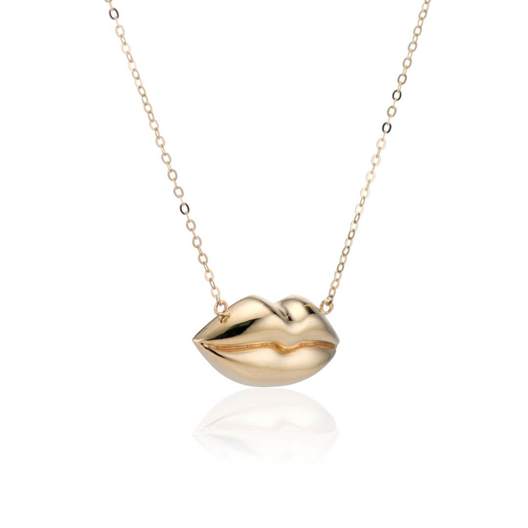 angled view of gold lips on a gold chain necklace on a white background