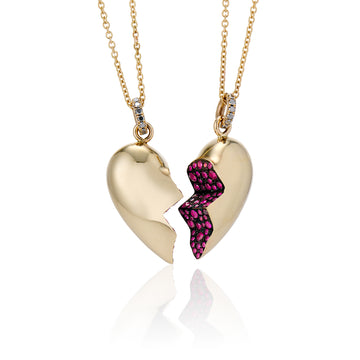 a set of two broken single heart necklaces made with ruby encrusted inner hearts are black rhodium plated, on a delicate chain necklace with black diamonds on bail angled view