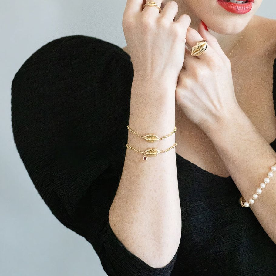 model wearing chic black dress modeling gold lips ring, earrings, bracelets and necklace